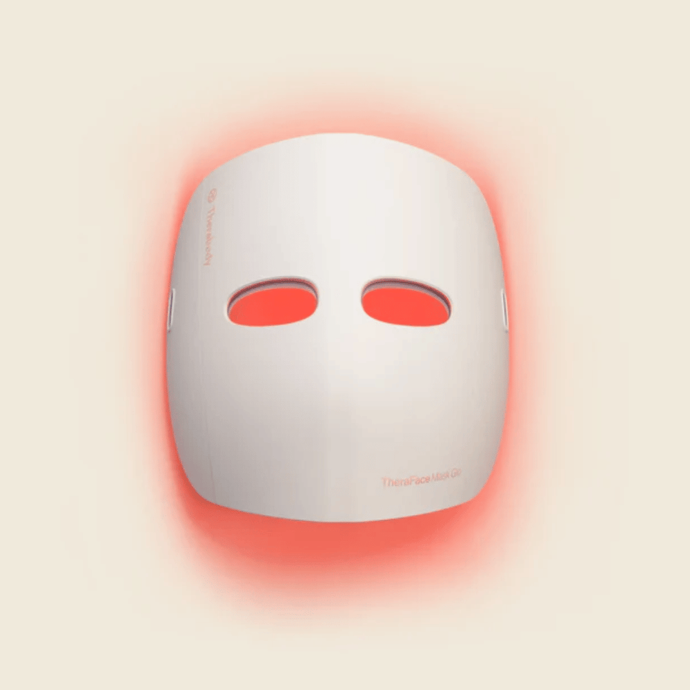 TheraFace Mask Glo | Therabody skincare device emitting red light for facial treatment and wellness enhancement.
