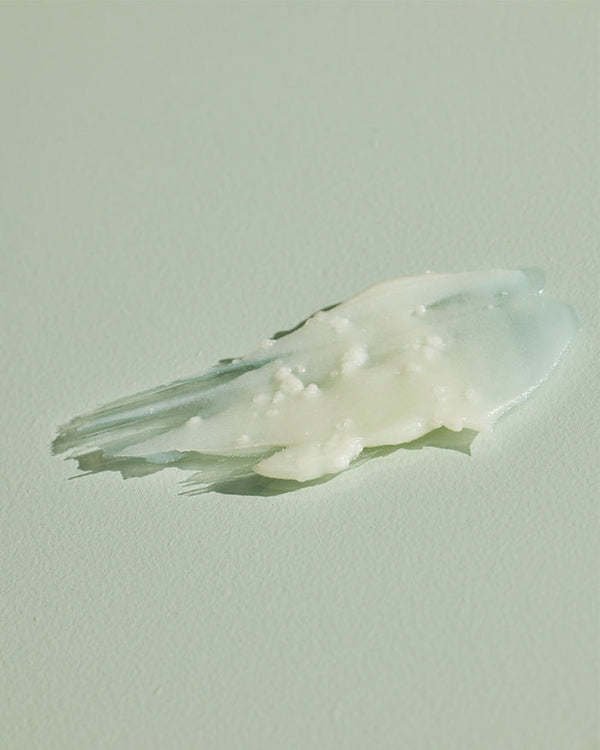 Close-up of creamy textured body salve with small granules on a light surface, representing Geranium Cedarwood BODY SALVE | Sparitual for skincare and body care.