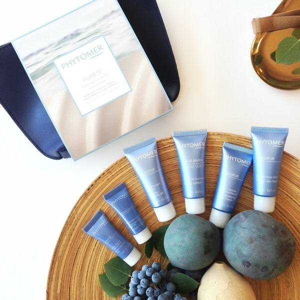 Purifying Starter Kit | Phytomer featuring blue skincare tubes arranged on a wooden tray with natural elements and a box in the background, highlighting a calm wellness aesthetic.