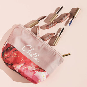 Drama & Shade Mini Mascara Set | Chella with four mini mascaras in different shades arranged beside a pink and red floral makeup bag with a gold zipper on a pale pink background