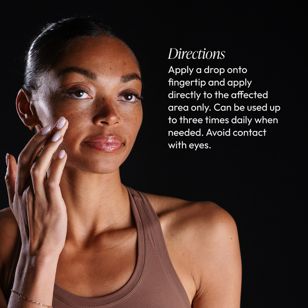 Woman with clear skin applying Spot Stop Blemish Corrector | Circadia to her cheek with fingertip, next to product usage directions text on a black background.