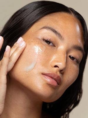 Close-up of a woman applying At-Home Facialist Peel | True Botanicals to her cheek, demonstrating a glowing skincare routine for healthy, radiant skin.