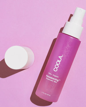 Rewakening™ Rosewater Mist Face Spray | COOLA in a pink spray bottle with white cap on a pink background, promoting organic skincare and hydration.