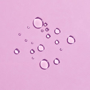 Close-up of clear water droplets on a soft pink surface representing hydration and freshness for Rewakening™ Rosewater Mist Face Spray | COOLA skincare.