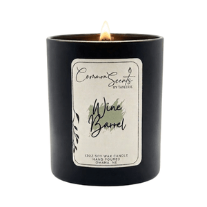 Lit Soft Crackling Wood Wick Candle | CommonScents in a sleek black container with a Wine Barrel scent label, showcasing a cozy and elegant ambiance for wellness and relaxation.