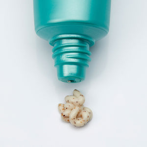 Close-up of a teal tube dispensing creamy exfoliating cream with natural grainy texture from Cyfolia Organic - Radiance Exfoliating Cream | Phytomer, skincare product.
