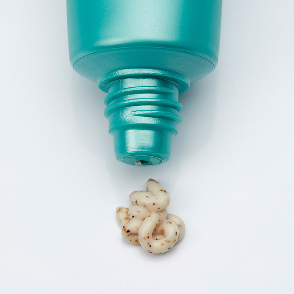 Close-up of a teal tube dispensing creamy exfoliating cream with natural grainy texture from Cyfolia Organic - Radiance Exfoliating Cream | Phytomer, skincare product.