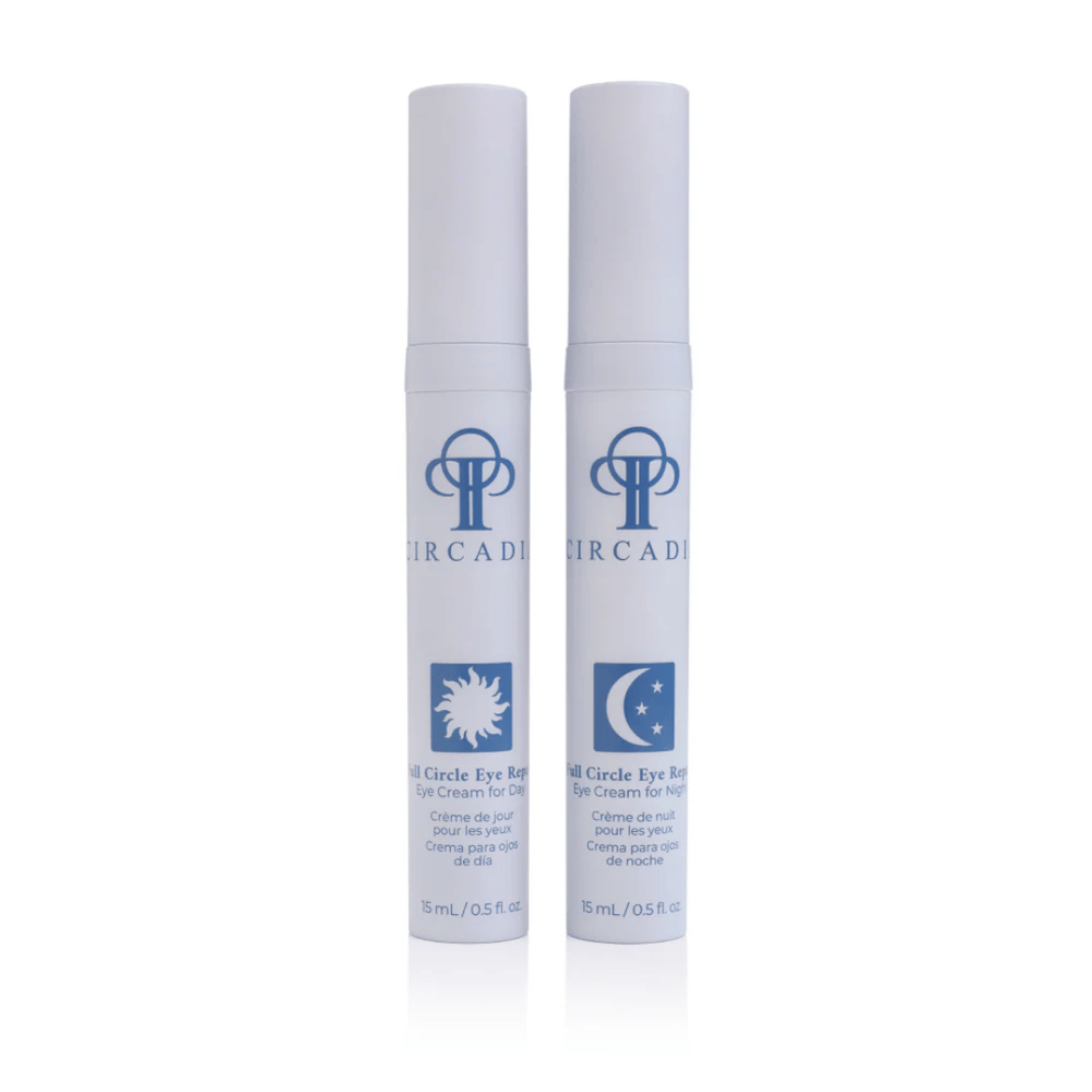 Two white cylindrical pump bottles of Full Circle Eye Repair - Eye Cream Duo | Circadia with blue branding, one for day use featuring a sun icon and one for night use featuring a moon icon, displayed on a white background.