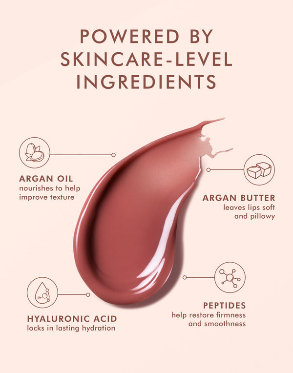 Close-up of a smooth, glossy swatch of Argan Butter Lip Balm | Moroccanoil with text highlighting skincare ingredients: argan oil, argan butter, hyaluronic acid, and peptides for hydration and softness.