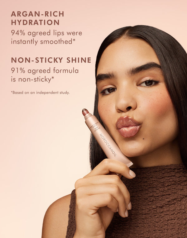 Woman with smooth skin holding Argan Butter Lip Balm | Moroccanoil near her lips, promoting argan-rich hydration and non-sticky shine for skincare and lip care.