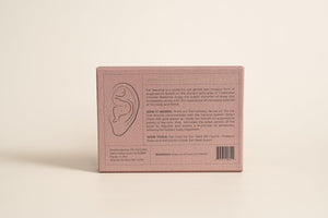 Back view of a pink box packaging for Detox and Cleanse - 24K Gold Ear Seed | Vie Healing showing product information and usage instructions with an ear illustration on a neutral background.