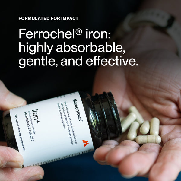 Close-up of hands holding an open bottle of Iron+ dietary supplement with capsules being poured into the palm, highlighting the product's formulation for gentle, highly absorbable iron.