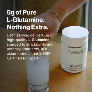 A hand holding a glass with a dissolving powder next to a white jar labeled Momentous containing L-Glutamine, highlighting a pure 5g serving of L-Glutamine supplement certified for sport.