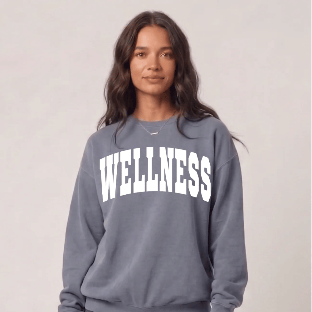 A woman wearing a blue Wellness Unisex Crew Neck Sweatshirt | Lucky Owl with white lettering, styled casually for a comfortable, wellness-inspired look.