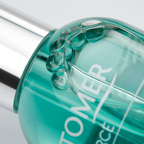 Close-up view of a turquoise serum bottle with silver cap and bubbles inside, featuring Oligoforce Advanced Wrinkle & Dark Spot Correction Moisturizing Serum with Oligomer | Phytomer for skincare.