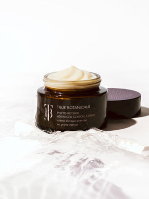 Open jar of Phyto-Retinol Advanced Clinical Cream | True Botanicals with smooth cream texture, placed on a white surface with a detached dark lid, showcasing luxury skincare product.