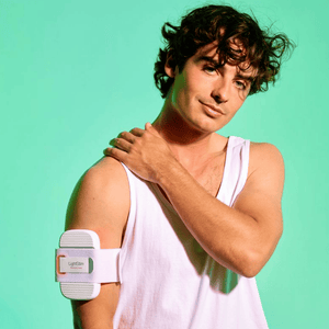 Man wearing a white tank top with a shoulder brace against a light green background