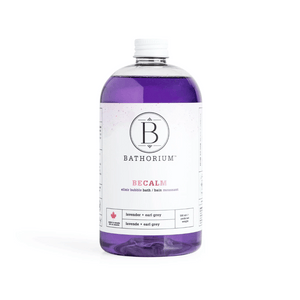 Clear bottle of BeCalm Bubble Elixir | Bathorium with purple lavender and earl grey bath elixir inside on a white background, promoting relaxation and wellness skincare.
