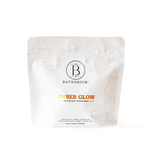 White resealable pouch of Amber Glow Clay Mineral Soak | Bathorium featuring subtle abstract line art and elegant black and orange text for skincare and wellness.