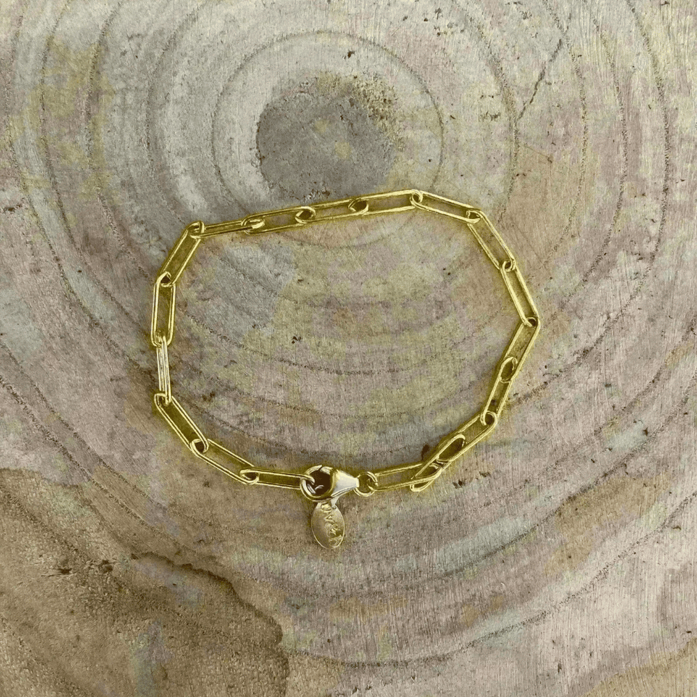 Gold Fill Chain Bracelet | Liv & B displayed on a textured wooden surface, featuring elongated gold chain links and a small clasp charm.