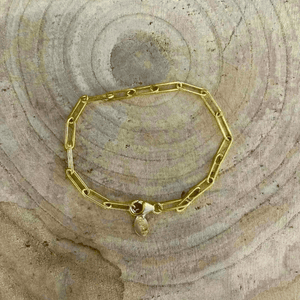Gold Fill Chain Bracelet | Liv & B displayed on a textured wooden surface, featuring elongated gold chain links and a small clasp charm.