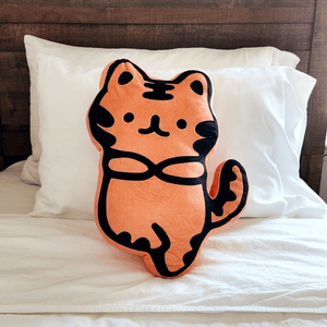 Soft orange and black plush toy shaped like a cute tiger sitting on a white bed with pillows, named Zen Tiger Plushie | Lucky Owl.