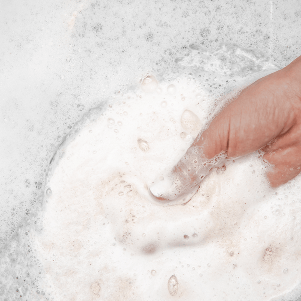 Hand mixing foamy water with Eucalyptus Apothecary Crush | Bathorium bath soak, highlighting a soothing and rejuvenating body care experience.