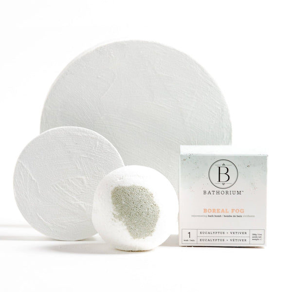 Boreal Fog Bath Bomb | Bathorium displayed with two textured white discs and its packaging, promoting skincare and wellness relaxation with eucalyptus and vetiver scents.