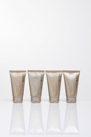 Four beige tubes of skincare products with green VOYA branding lined up, showcasing the Organic Voyager Travel Set | VOYA for body care and wellness.