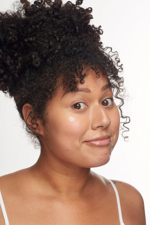 Young woman with curly hair and natural skin tone wearing several transparent acne patches on her face, demonstrating the Breakout Box 3-In-1 Acne Treatment Kit | Patchology for clear skincare.