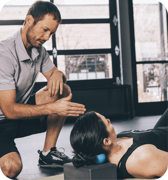 A man guides a woman using the RAD Roller Soft | RAD for targeted muscle recovery and body care, demonstrating its use on her upper back and neck in a wellness setting.