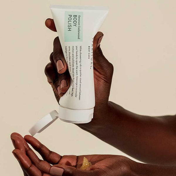 Person holding and dispensing Geranium Cedarwood BODY POLISH | Sparitual skincare product onto their hand against a neutral background, showcasing body care for wellness.