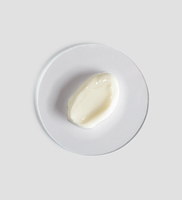 Close-up of a smooth, creamy white skincare product texture displayed on a clear round surface, representing Renight Cream | [ comfort zone ] for body care and wellness.