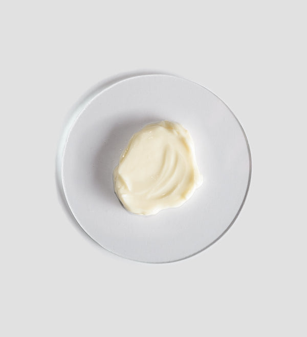 A smooth dollop of moisturizing cream on a white plate, representing the texture of Sacred Nature Hydra Cream | [ comfort zone ] skincare product.