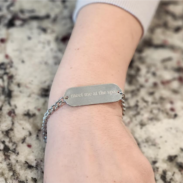 Reversible Engraved ID Bracelet (unisex) - Cute Spa Bunny | Lucky Owl featuring a silver chain and metal plate engraved with "meet me at the spa" worn on a wrist.