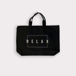 Black canvas tote bag with double handles and zipper top featuring the word RELAX inside a white rectangular outline, Relax Tote Bag w/ Zipper Top | Lucky Owl
