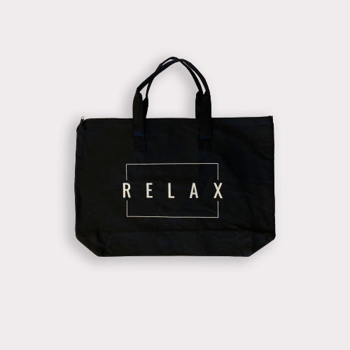 Black canvas tote bag with double handles and zipper top featuring the word RELAX inside a white rectangular outline, Relax Tote Bag w/ Zipper Top | Lucky Owl