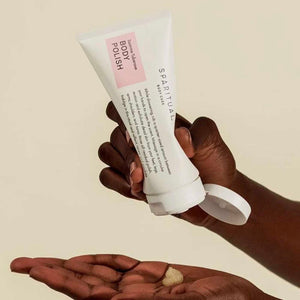 Hand holding an open tube of Jasmine Tuberose BODY POLISH | Sparitual dispensing body polish onto the other palm, showcasing skincare and body care wellness product.