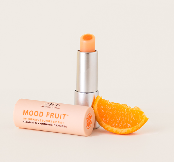 Orange Mood Fruit™ Lip Therapy | Farmhouse Fresh lip balm displayed with a fresh orange slice, highlighting vitamin C and organic orange ingredients for skincare and lip care wellness.