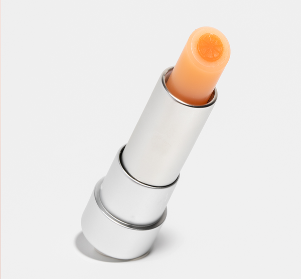 Orange Mood Fruit™ Lip Therapy | Farmhouse Fresh in a silver tube with an orange-colored balm featuring a detailed fruit design on top, ideal for skincare and lip care.