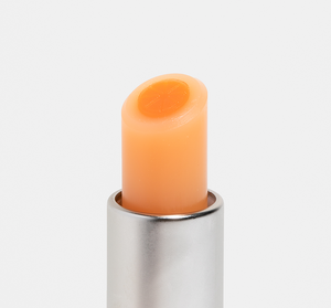 Close-up of Orange Mood Fruit™ Lip Therapy | Farmhouse Fresh in a silver tube, showing smooth, orange-toned lip balm designed for moisturizing and nourishing lips.