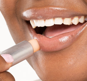 Close-up of a person applying Orange Mood Fruit™ Lip Therapy | Farmhouse Fresh lip balm to moisturize and protect lips for smooth, healthy skin.