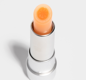 Orange Mood Fruit™ Lip Therapy | Farmhouse Fresh lip balm in a silver tube with an orange fruit design embedded in the peach-colored balm, highlighting skincare and wellness.