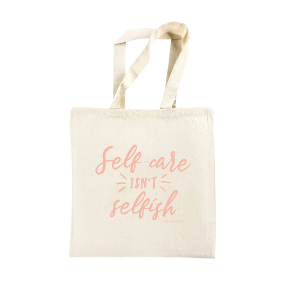 Natural cotton tote bag with pink script text reading "Self-care isn't selfish," featuring the phrase prominently on a simple, lightweight design called Self-Care Isn't Selfish Lightweight Tote | Lucky Owl.