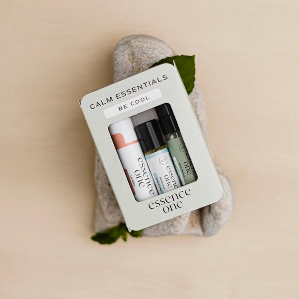 Calm Essentials Kit - "Be Cool" | Essence One wellness set featuring three small skincare and aromatherapy products arranged on smooth stones with green leaves.
