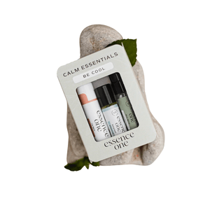Calm Essentials Kit - "Be Cool" | Essence One containing three wellness roller bottles displayed on smooth white stones with green leaves for a natural, soothing aesthetic.