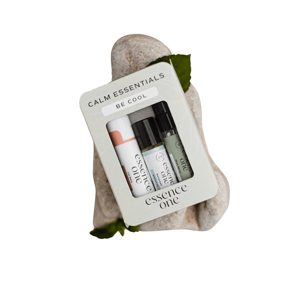 Calm Essentials Kit - "Be Cool" | Essence One containing three wellness roller bottles displayed on smooth white stones with green leaves for a natural, soothing aesthetic.